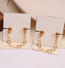 将图片加载到图库查看器,Pair of hypoallergenic surgical stainless steel double piercing earrings, featuring heart studs connected by a delicate chain, plated in gold