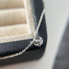 Load image into Gallery viewer, A necklace featuring a 6.5mm round cut moissanite gemstone, suspended from a delicate chain, showcasing exceptional brilliance and elegance.
