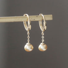 Load image into Gallery viewer, 18K gold-plated surgical steel hoop earrings with 16mm hoop and 8mm freshwater button pearls in peach. Total length of 3.5-4cm. Elegantly designed for any occasion.
