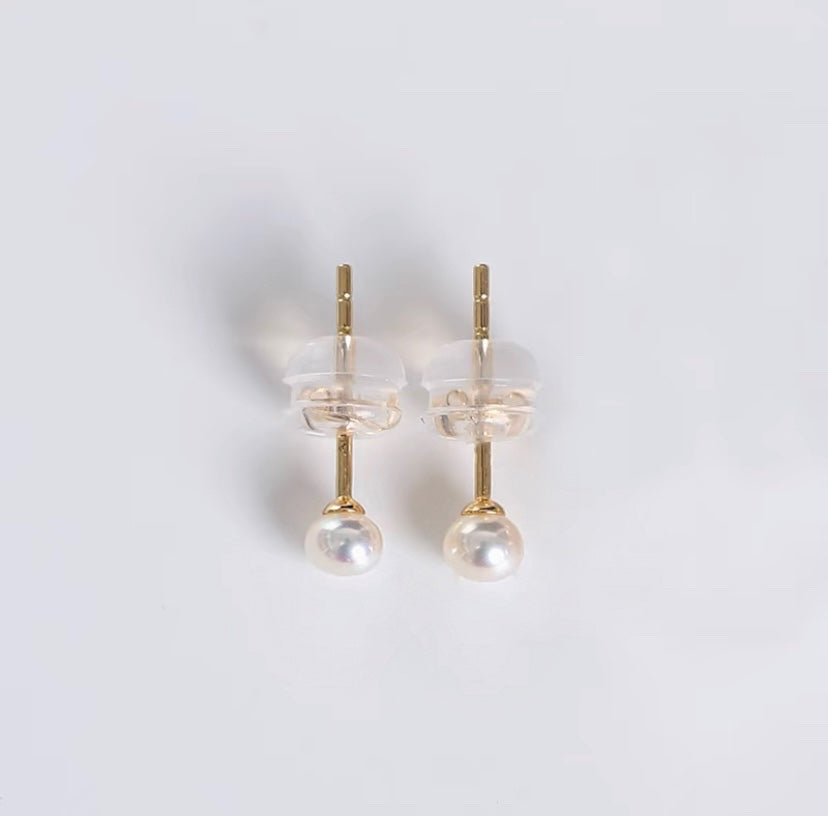 A pair of 14K solid gold earrings featuring lustrous AAA-grade button freshwater pearls, known for their exceptional quality and shine.