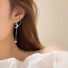 Load image into Gallery viewer, A pair of solid stainless steel earrings featuring a moon and star design connected by a delicate chain. The earrings measure 6cm in length, adding a touch of celestial charm to any outfit.
