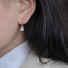 이미지를 갤러리 뷰어에 로드 , A pair of 18K gold plated dangle earrings featuring 6x8mm pear cut zirconia crystals, designed with minimalist ear wires for an elegant and sparkling look.
