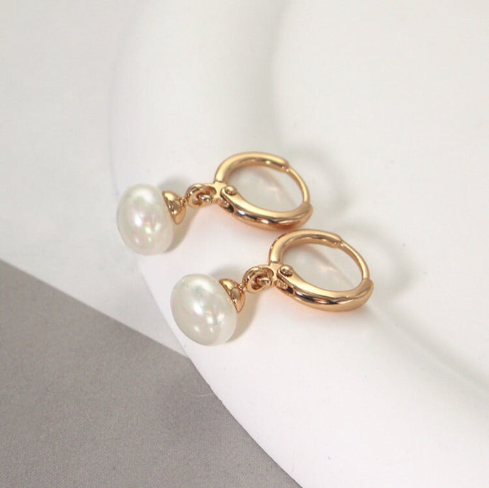 18K gold-plated hoop earrings with 4mm half-drilled button pearls. Huggie style for comfortable all-day wear, adding a classic accent to any outfit.