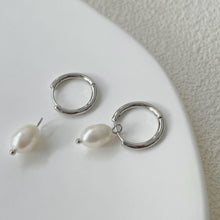 Load image into Gallery viewer, Huggie hoop earrings made of surgical stainless steel, featuring 6mm or 8mm freshwater pearls, showcasing a minimalist and elegant design.
