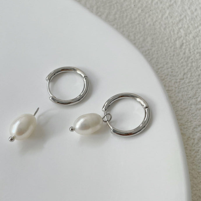 Huggie hoop earrings made of surgical stainless steel, featuring 6mm or 8mm freshwater pearls, showcasing a minimalist and elegant design.