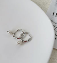 Load image into Gallery viewer, Huggie hoop earrings made of surgical stainless steel, featuring 6mm or 8mm freshwater pearls, showcasing a minimalist and elegant design.
