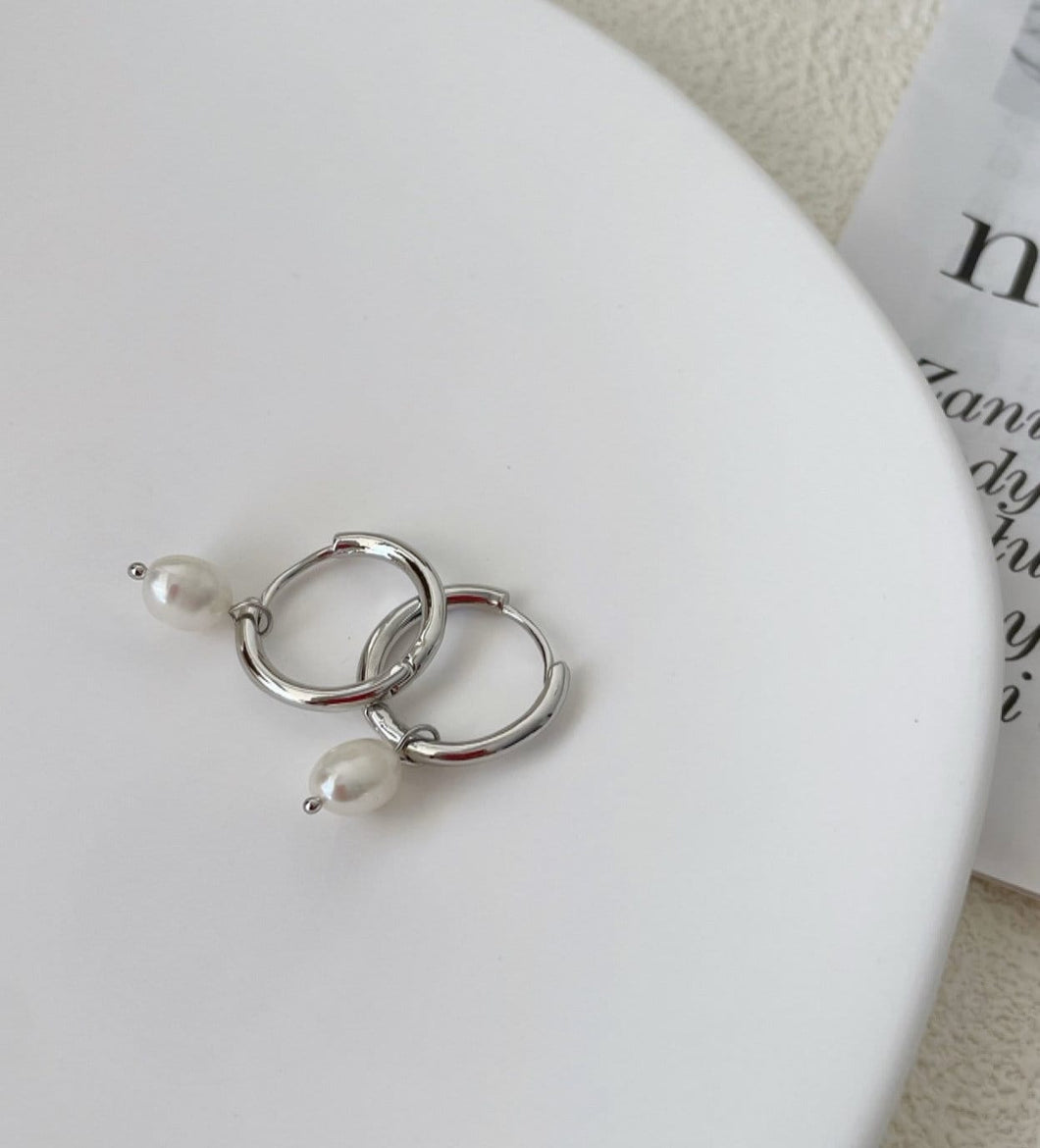 Huggie hoop earrings made of surgical stainless steel, featuring 6mm or 8mm freshwater pearls, showcasing a minimalist and elegant design.