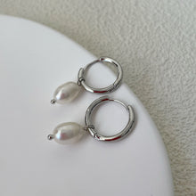 Load image into Gallery viewer, Huggie hoop earrings made of surgical stainless steel, featuring 6mm or 8mm freshwater pearls, showcasing a minimalist and elegant design.
